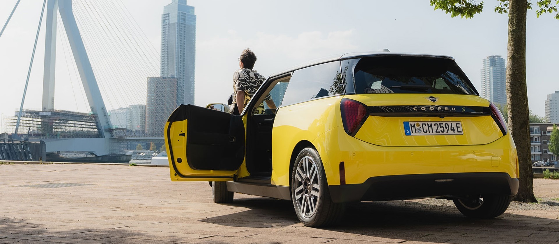 Yellow MINI Cooper parked near a city waterfront with open door